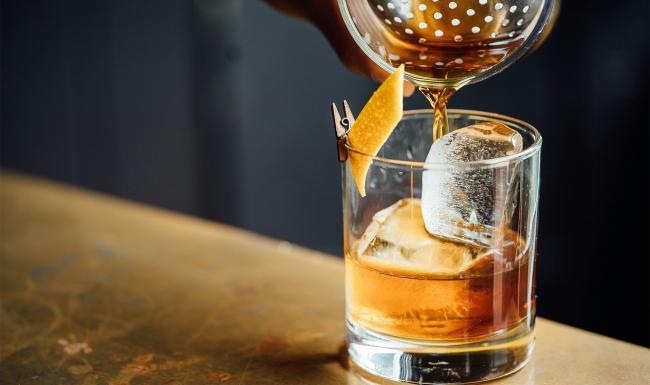 a glass of liquid being poured into a glass with ice