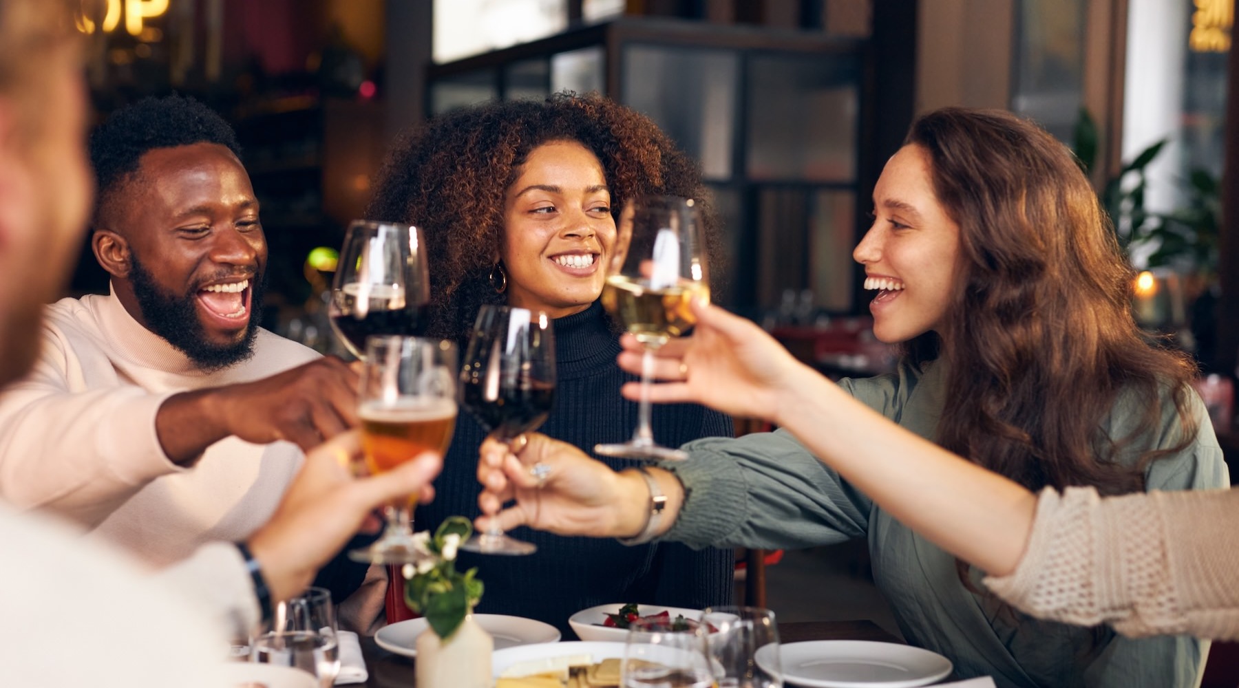 a group of people out at dinner holding wine glasses in the air